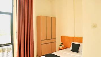 A hotel room with a bed, a wardrobe, a nightstand, and a window with curtains.