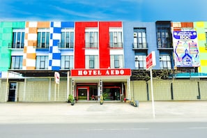 A hotel with a red sign, multiple balconies, and a colorful facade.