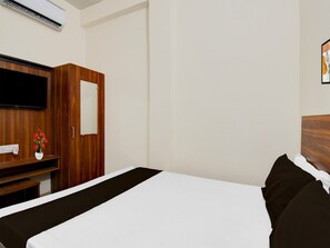 A hotel room with a bed, a wooden wardrobe, a flat-screen TV, and a wall-mounted air conditioner. - Hotel O BHU Campus (Varanasi)
