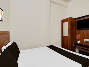 A hotel room with a bed, a wooden wardrobe, a television, and a small vase with flowers. - Hotel O BHU Campus (Varanasi)