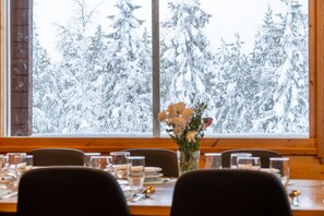 A dining table set with glasses, plates, and cutlery, with a vase of flowers in the center. - Rukakorpi 3 by Holiday in Lapland (Ruka)
