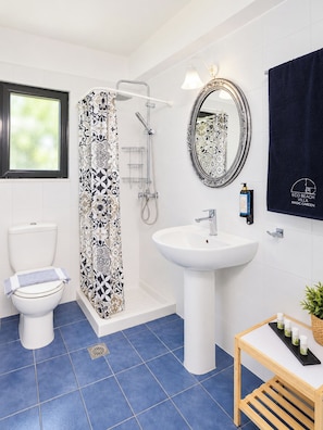 Ein Badezimmer mit Dusche, Toilette, Waschbecken und Spiegel.