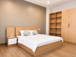 Un dormitorio con una cama de madera, mesita de noche y estantería empotrada de madera.