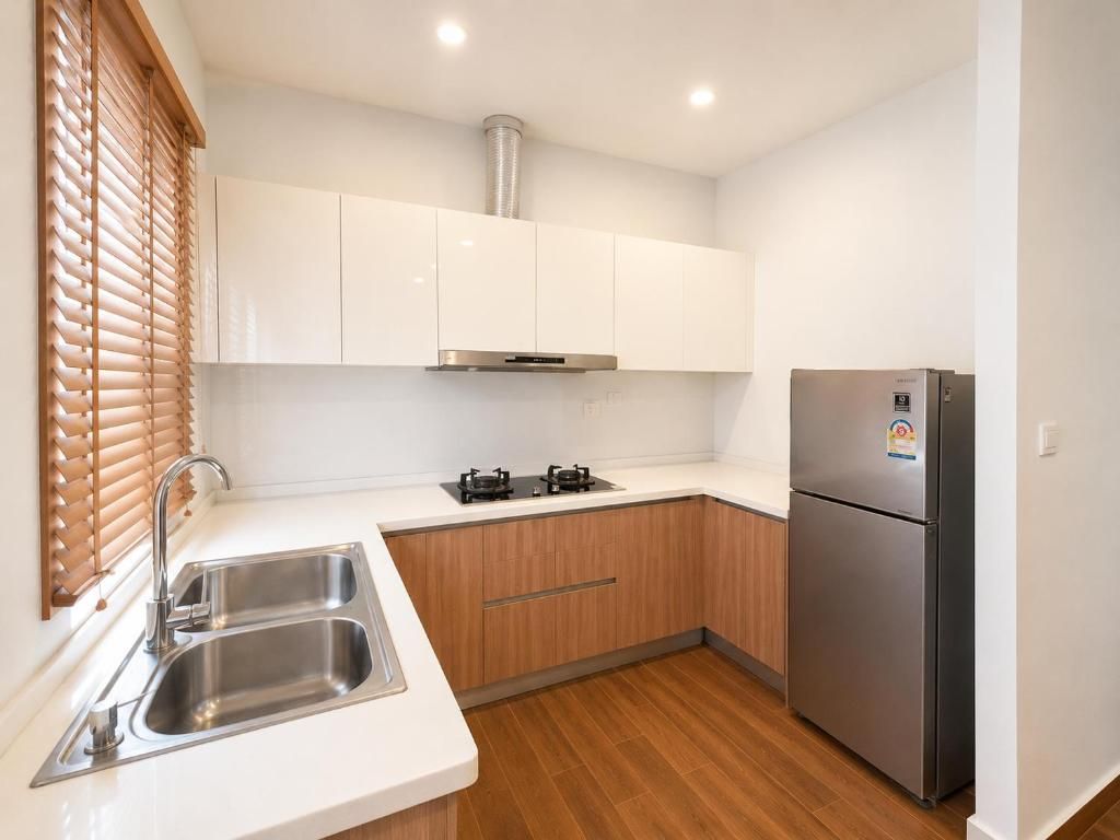 Eine kompakte Küche mit Edelstahlspüle, Holzschränken, Backofen und Kühlschrank.