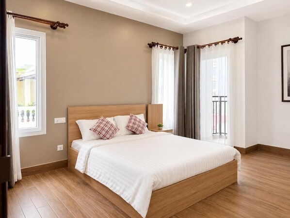 A bedroom with a wooden bed, white bedding, and a view of the outdoors through a window.