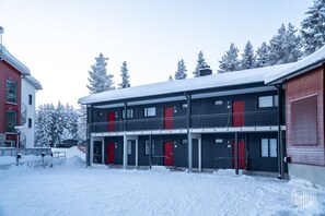 Ein zweistöckiges Gebäude mit einer roten Tür und einem Balkon.