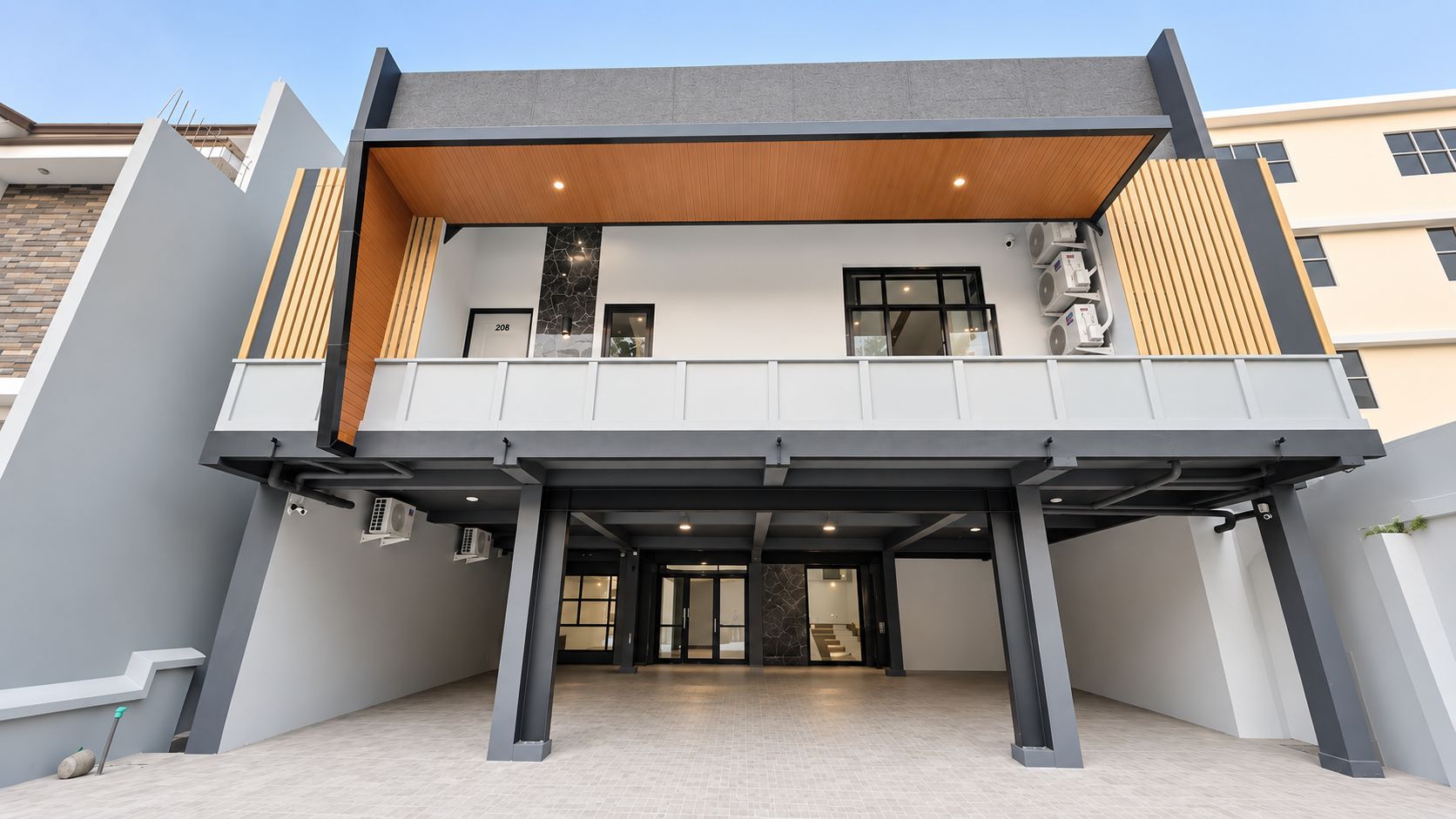 A modern building with a flat roof, a covered entrance area, and a visible staircase leading to the upper floor.