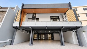 Een modern gebouw met een plat dak, een overdekte entree en een zichtbare trap die naar de bovenverdieping leidt.