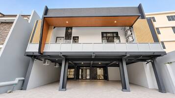 A modern building with a flat roof, a covered entrance area, and a visible staircase leading to the upper floor.