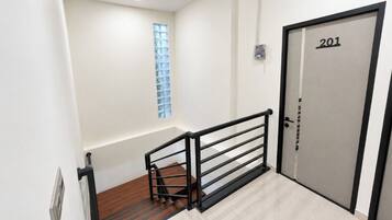 A staircase with a metal railing, a door with the number 201, and a window with a grid pattern.