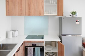 A modern kitchen with wooden cabinets, a built-in oven, a refrigerator, and a toaster. - Stylish 3BR Ensuite, CBD, Car Park, Stadium Nearby (Christchurch)