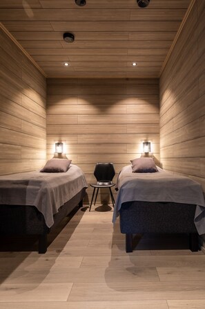 A room with two beds, a chair, and wall-mounted lights. - Villa SnowLife A by Holiday in Lapland (Levi)