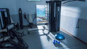 Een sportschool met trainingsapparatuur, een blauwe fitnessbal en gewichten.