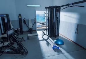Ett gym med träningsutrustning, en blå träningsboll och hantlar.