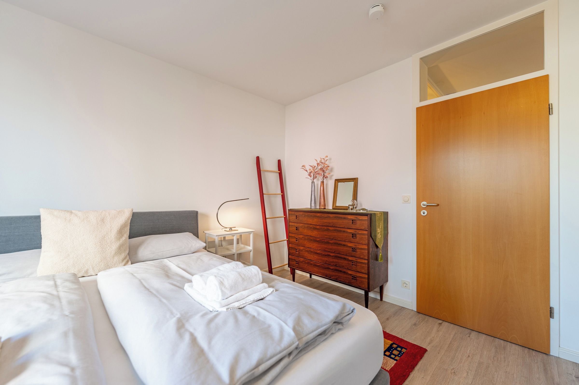 A hotel room with a bed, a dresser, a mirror, and a door.