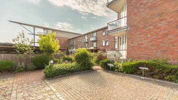 Een binnentuin met een bakstenen gebouw, een verhard pad en diverse beplanting.