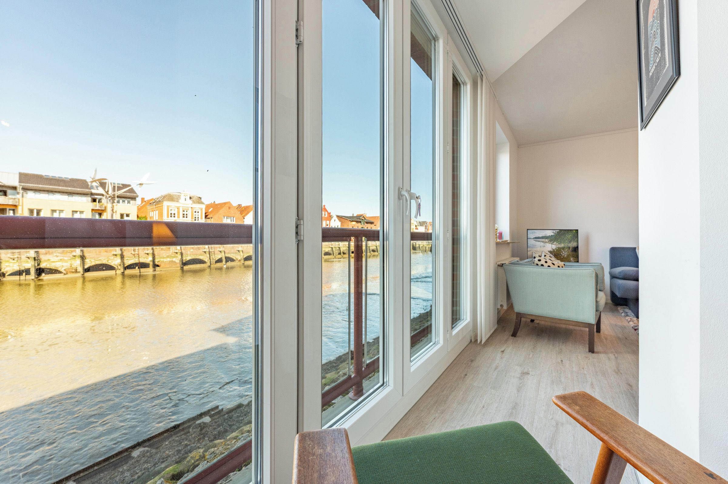 Ein Zimmer mit großen Fenstern mit Blick auf einen Fluss, einer Holzbank und einem kleinen Tisch mit einem Stuhl.
