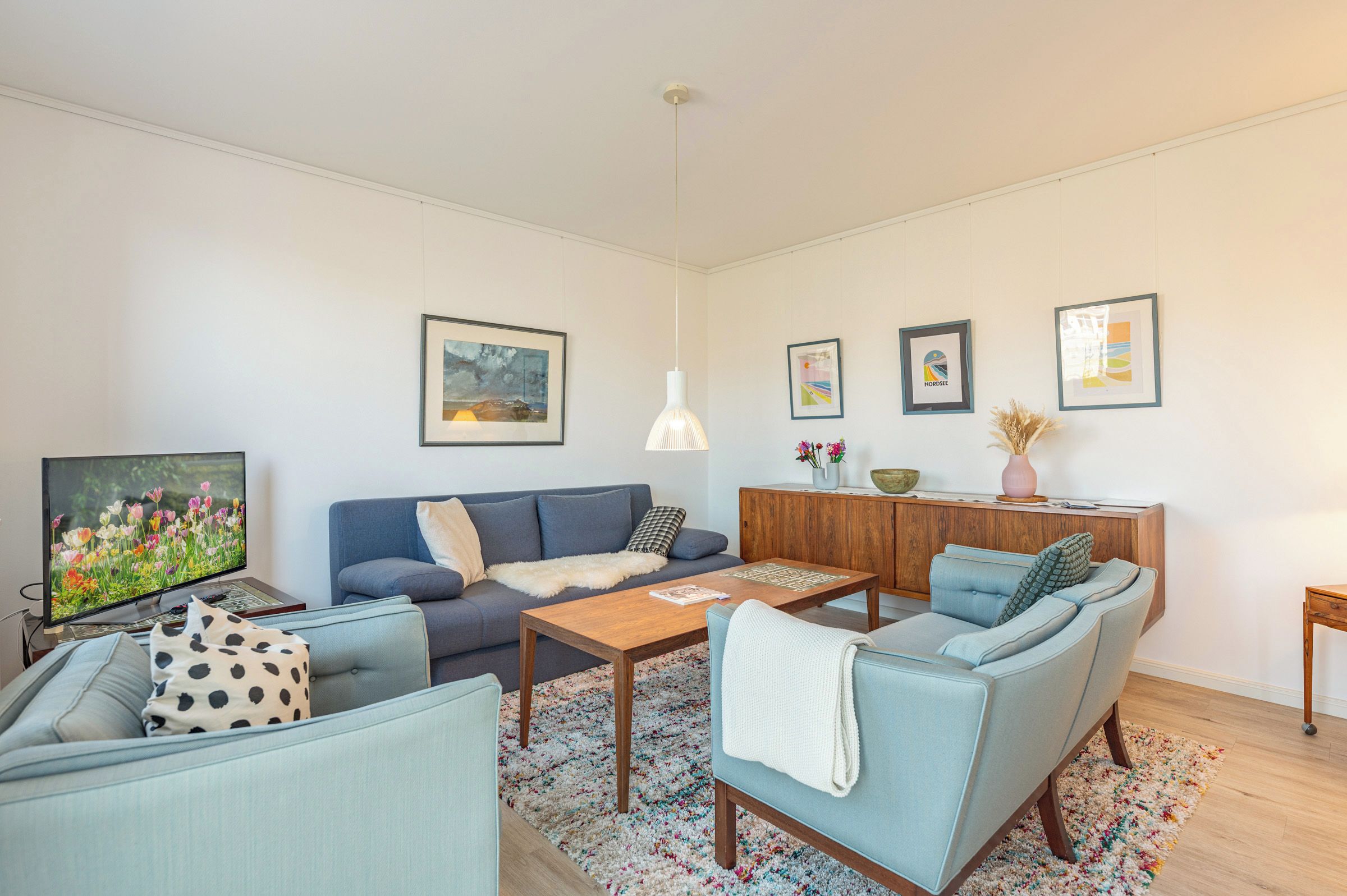 Una sala de estar con sofá, mesa de centro, televisor y mueble.