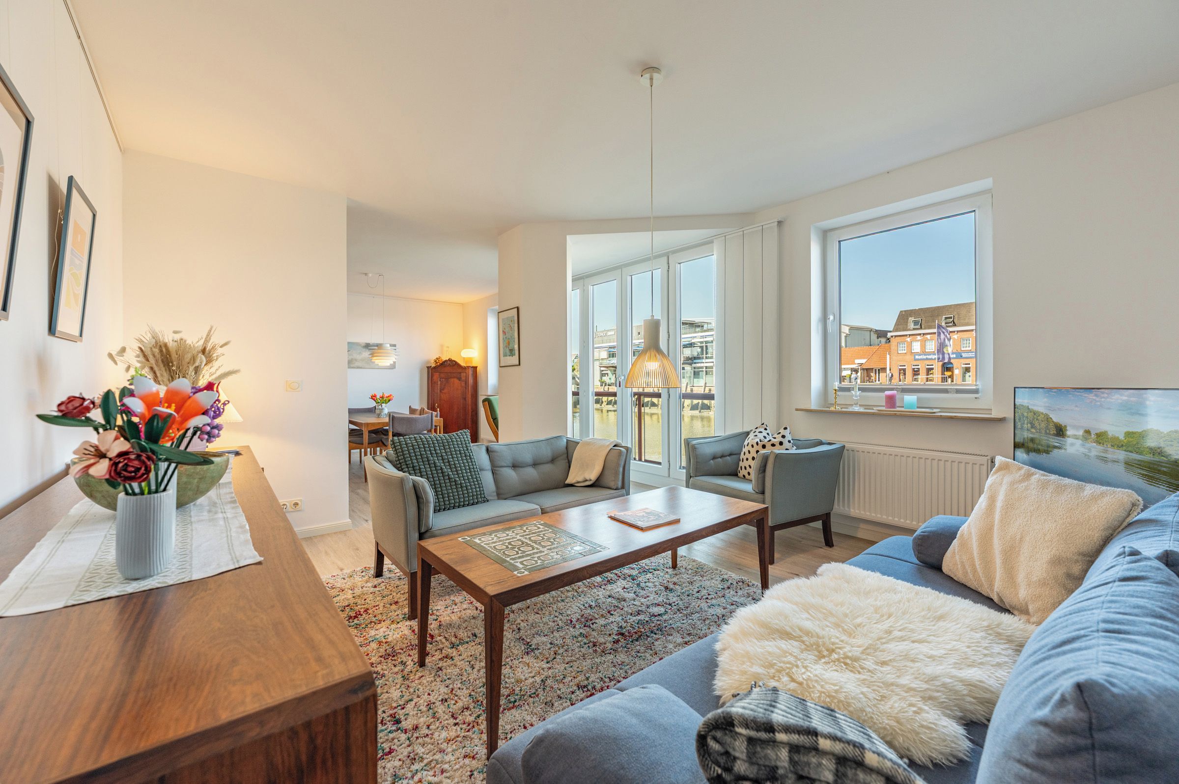 Een moderne woonkamer met een bank, salontafel en een eethoek met een tafel en stoelen.