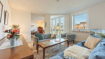 Een moderne woonkamer met een bank, salontafel en een eethoek met een tafel en stoelen.