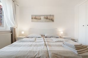 Habitación de hotel con dos camas, un cuadro en la pared y una ventana con cortinas.