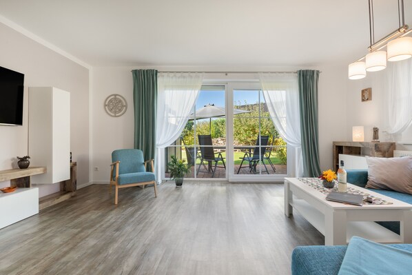 Ein modernes Wohnzimmer mit einer großen Glasschiebetür, die zu einer Außenpatio führt.