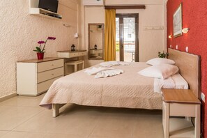 Ein Hotelzimmer mit Bett, Nachttisch, Kommode und Fernseher an der Wand.