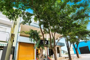 A multi-story building with a closed yellow shutter, a sign indicating 'Hotel,' and a clear blue sky. - Hotel O K R Puram Manyata (Bengaluru)