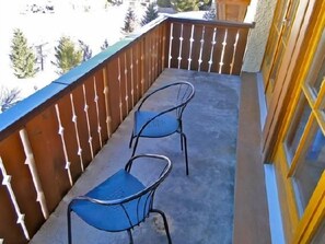 A balcony with two metal chairs and a wooden railing. - Two-room apartment on the top floor (4th floor), approximately 60 m². (Celerina/Schlarigna)