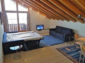 Une chambre avec un lit, un canapé, une télévision et un balcon.