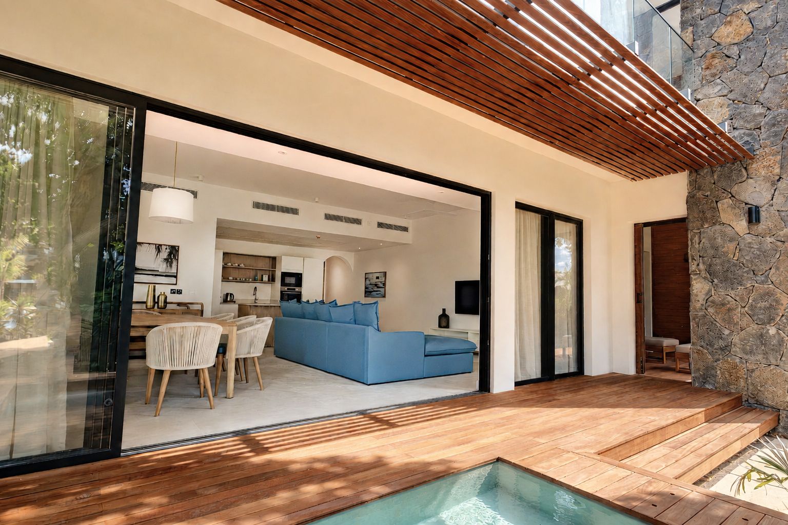 A modern interior with a dining area, a blue sofa, and a stone wall.