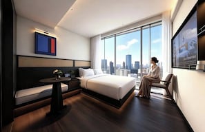 A modern hotel room with a large bed, a seating area, a small table, and a city view. - Ruilan (Guangzhou)