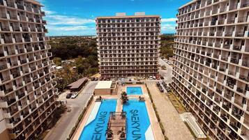 Un immeuble de grande hauteur doté de nombreux balcons et d’un espace piscine central arborant la marque « SAEKYUNG ».