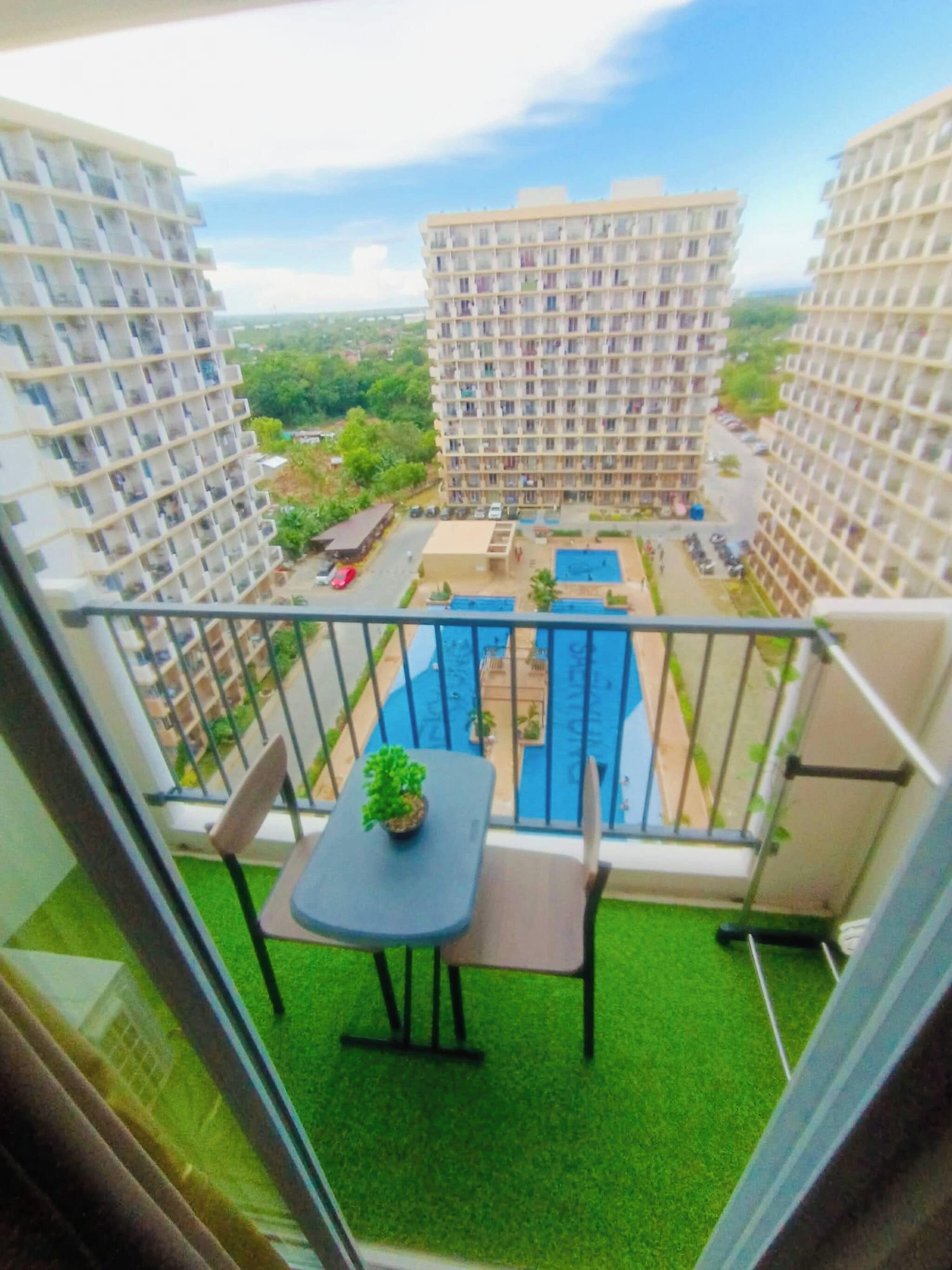 A balcony with a table and chairs, a small pool, and a view of surrounding buildings.