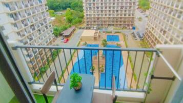 A balcony with a table and chairs, a small pool, and a view of surrounding buildings.
