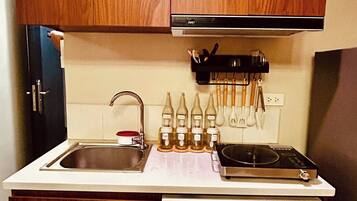 Una cucina compatta con mobili in legno, lavatrice integrata e un piano di lavoro con diversi utensili da cucina.