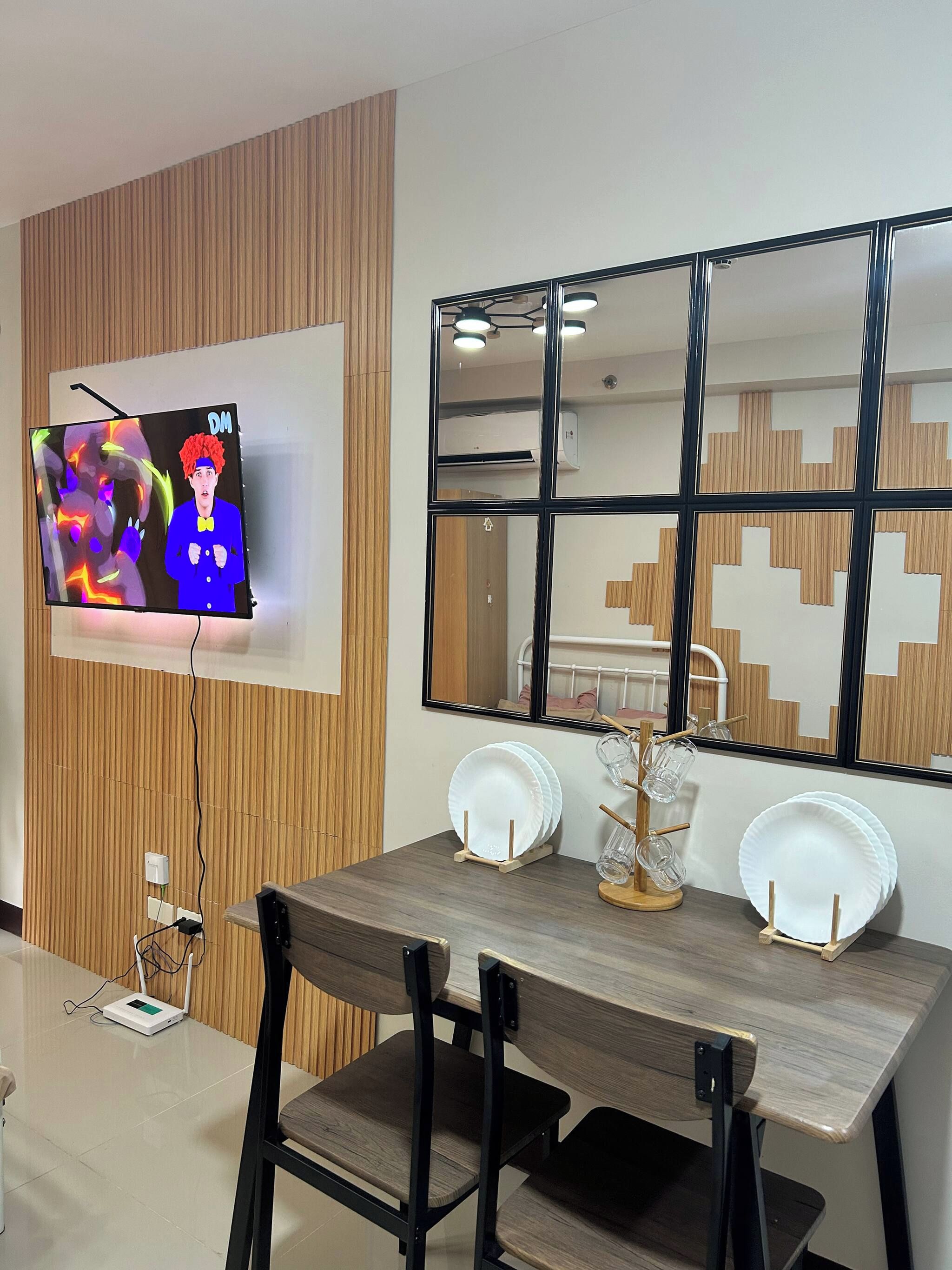 Un espace repas moderne avec un mur en bois, un téléviseur fixé au mur et une table à manger avec des chaises.