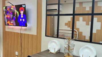 Un espace repas moderne avec un mur en bois, un téléviseur fixé au mur et une table à manger avec des chaises.