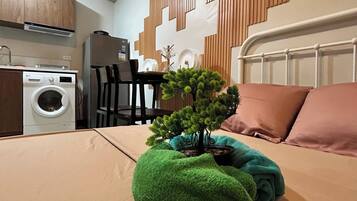 A hotel room with a bed, a small green plant, a remote control, and a QR code on the bed.
