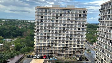 A high-rise residential building with multiple balconies, a swimming pool, and a parking area.