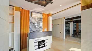 A reception area with a modern design, including a reception desk labeled 'RECEPTION Collection Company Services,' a ceiling fan, and a fire extinguisher.