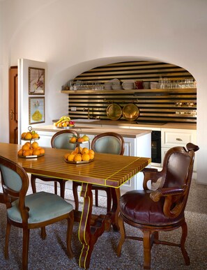 A dining area with a striped table, chairs, and a kitchen with a striped backsplash. - Le Nonne Suite (Chieri)