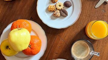 A breakfast setting with croissants, bread, fruit, and a variety of spreads on plates.