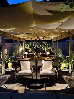 An outdoor seating area with a canopy, tables with lamps, and potted plants. - La Vilma Su﻿ite private living room bathroom two balconies shared garden, (Piedmont)