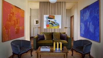 A living room with a green sofa, two armchairs, a coffee table, and three paintings.