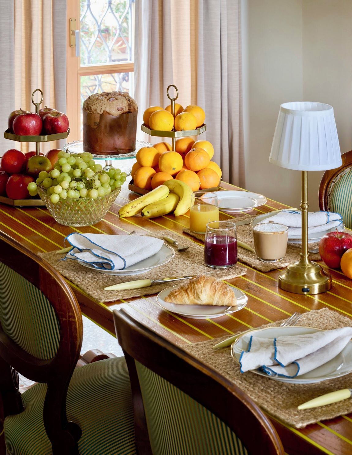 Une table de petit-déjeuner avec des fruits, un croissant et des boissons.