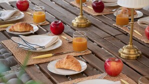 A wooden picnic table set with plates, croissants, apples, and glasses of orange juice. - La Giovanna guest room features a sumptuous antique bed that (Chieri)