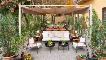 An outdoor seating area with a white sofa, two round tables, and multiple chairs.