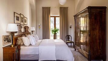 Une chambre d’hôtel avec un grand lit, deux tables de chevet avec des lampes, une armoire et une fenêtre avec des rideaux.