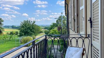 Ein Balkon mit einem Metallgeländer, einem weißen Sitzmöbel und Blick auf eine grüne Landschaft.